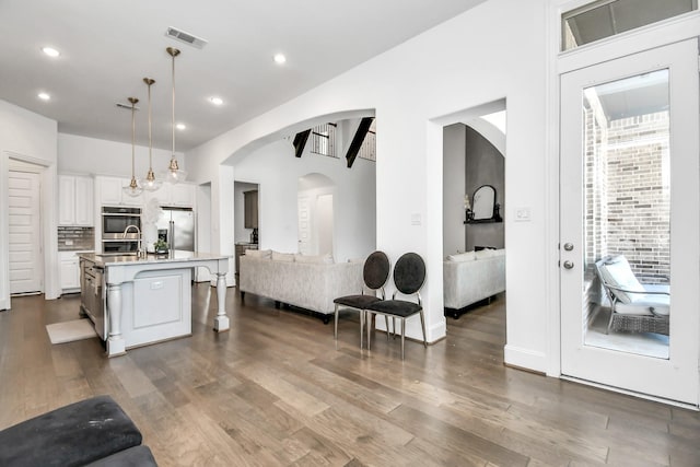 kitchen featuring pendant lighting, an island with sink, white cabinets, a kitchen bar, and stainless steel appliances