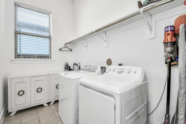 clothes washing area with cabinets, light tile patterned flooring, and washer and clothes dryer