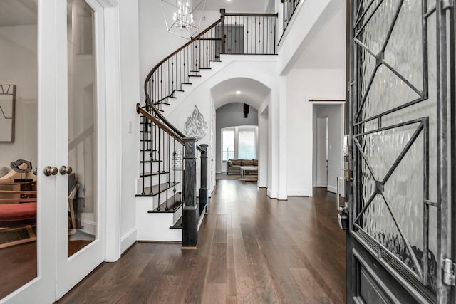 foyer entrance featuring a high ceiling, dark hardwood / wood-style floors, a chandelier, and french doors