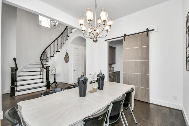 dining space with a barn door, an inviting chandelier, and dark hardwood / wood-style flooring