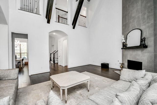 living room featuring dark hardwood / wood-style flooring, a tile fireplace, and a high ceiling