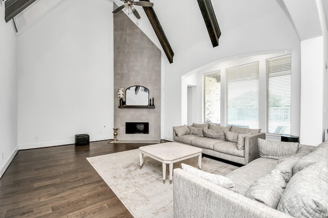 living room with ceiling fan, beam ceiling, high vaulted ceiling, dark hardwood / wood-style floors, and a large fireplace