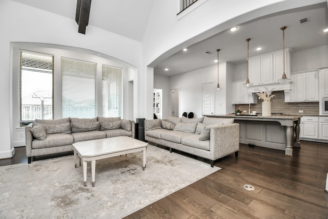 living room with dark wood-type flooring and high vaulted ceiling