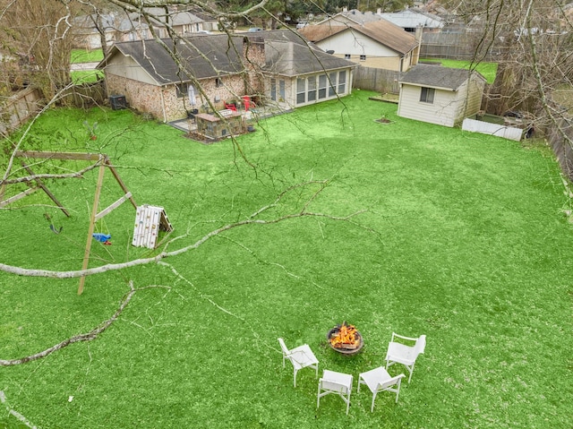 view of yard with a storage unit, a fenced backyard, a fire pit, and an outbuilding