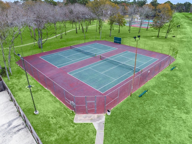 view of sport court with fence and a lawn