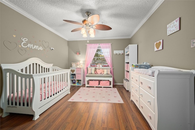 bedroom with a crib, crown molding, a textured ceiling, and dark hardwood / wood-style flooring