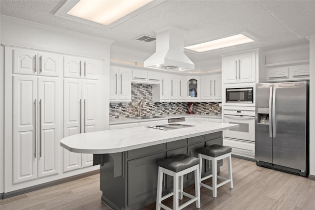 kitchen featuring stainless steel appliances, a breakfast bar, a sink, white cabinets, and custom range hood