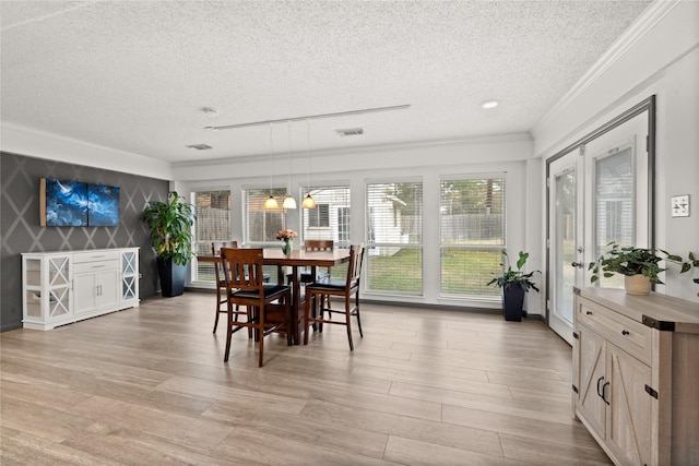 dining room featuring ornamental molding, light hardwood / wood-style floors, and a textured ceiling