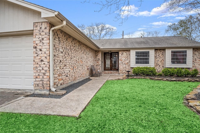 view of exterior entry featuring a yard, brick siding, and an attached garage