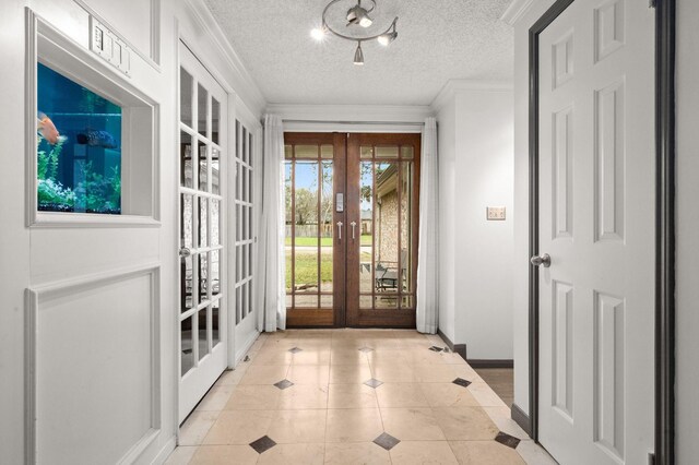 doorway with a textured ceiling, french doors, light tile patterned floors, and crown molding