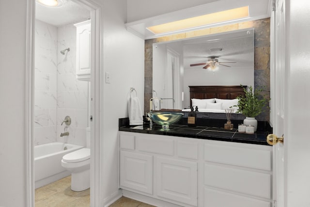 full bathroom with tiled shower / bath, vanity, ceiling fan, toilet, and a textured ceiling