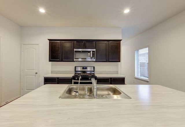 kitchen featuring stainless steel appliances, dark brown cabinets, and sink