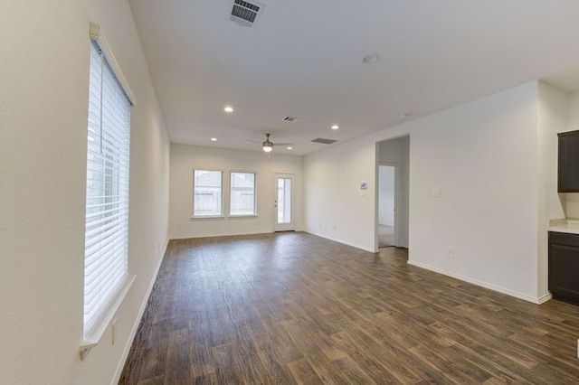 unfurnished living room featuring dark wood-type flooring and ceiling fan