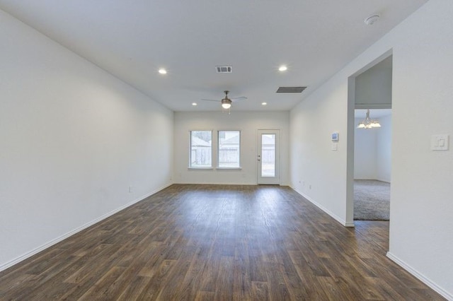 spare room with dark wood-type flooring and ceiling fan with notable chandelier