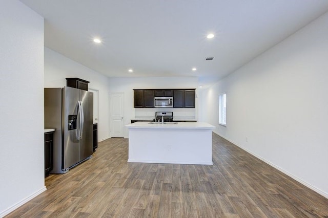 kitchen featuring sink, appliances with stainless steel finishes, hardwood / wood-style floors, dark brown cabinets, and a center island with sink