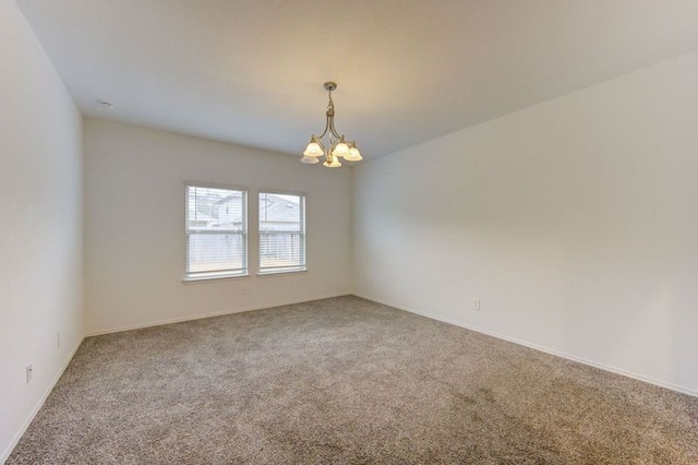 spare room with an inviting chandelier and carpet