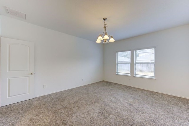 carpeted spare room with an inviting chandelier