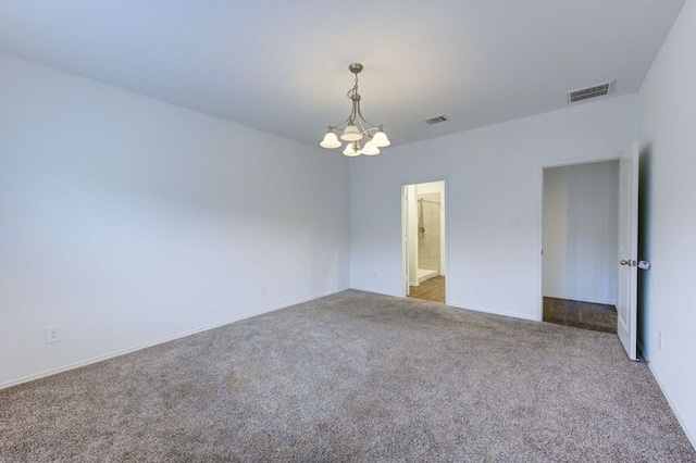 carpeted spare room with a notable chandelier