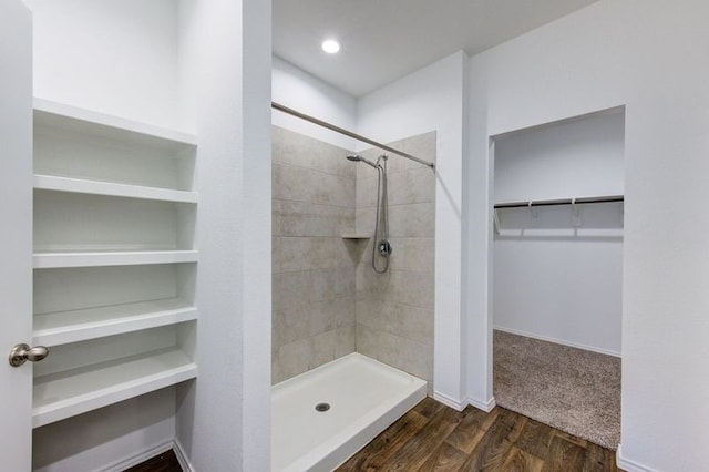 bathroom with a tile shower, hardwood / wood-style flooring, and built in shelves