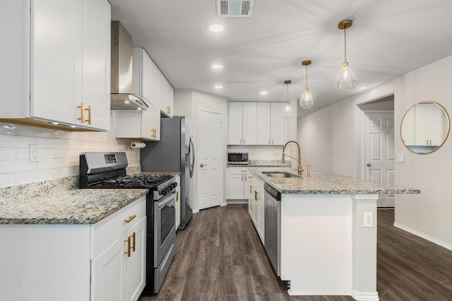 kitchen with hanging light fixtures, wall chimney exhaust hood, stainless steel appliances, sink, and white cabinetry