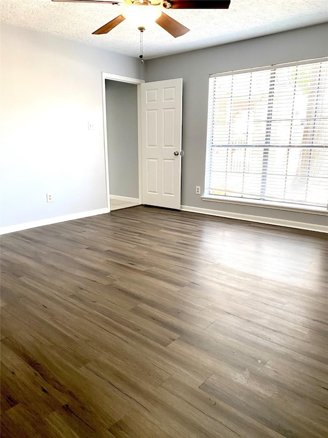 unfurnished room featuring ceiling fan, dark wood-type flooring, and a textured ceiling