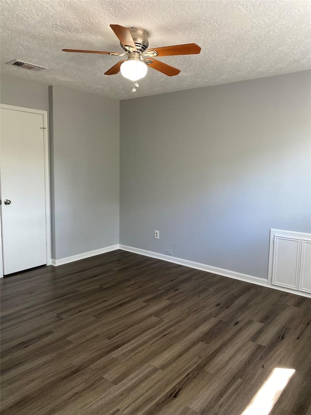 empty room with ceiling fan, dark hardwood / wood-style flooring, and a textured ceiling