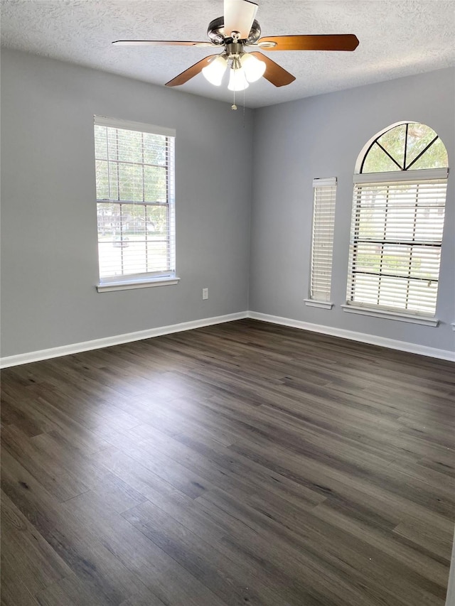 spare room featuring dark wood-type flooring, ceiling fan, and a textured ceiling