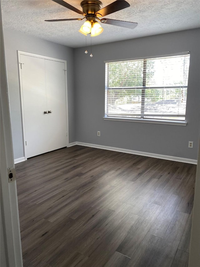 unfurnished bedroom featuring dark wood-type flooring, multiple windows, and a textured ceiling