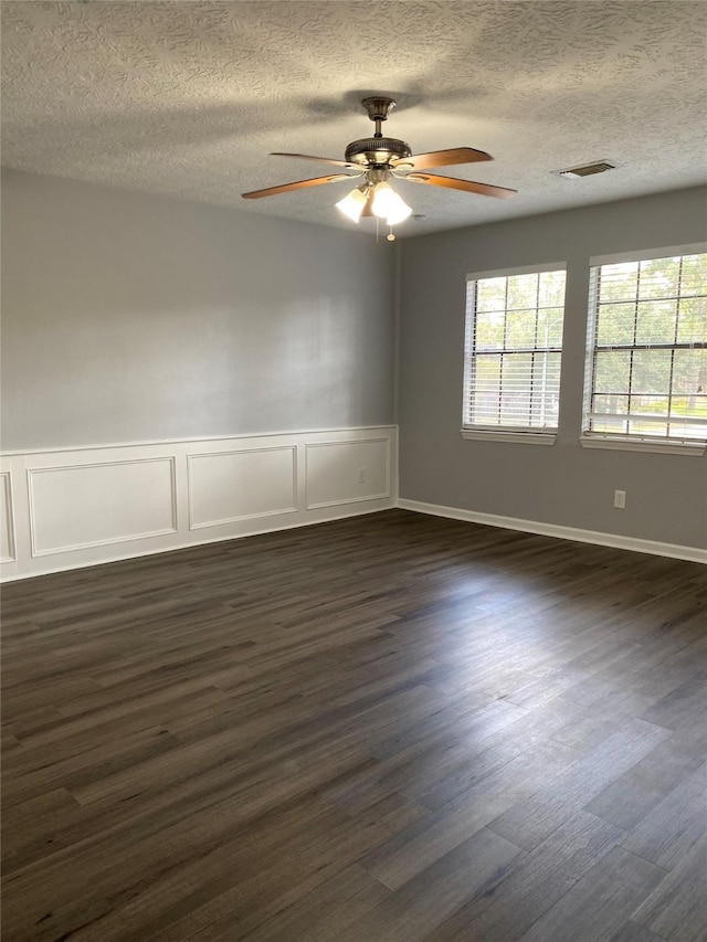 empty room with dark wood-type flooring, ceiling fan, and a textured ceiling