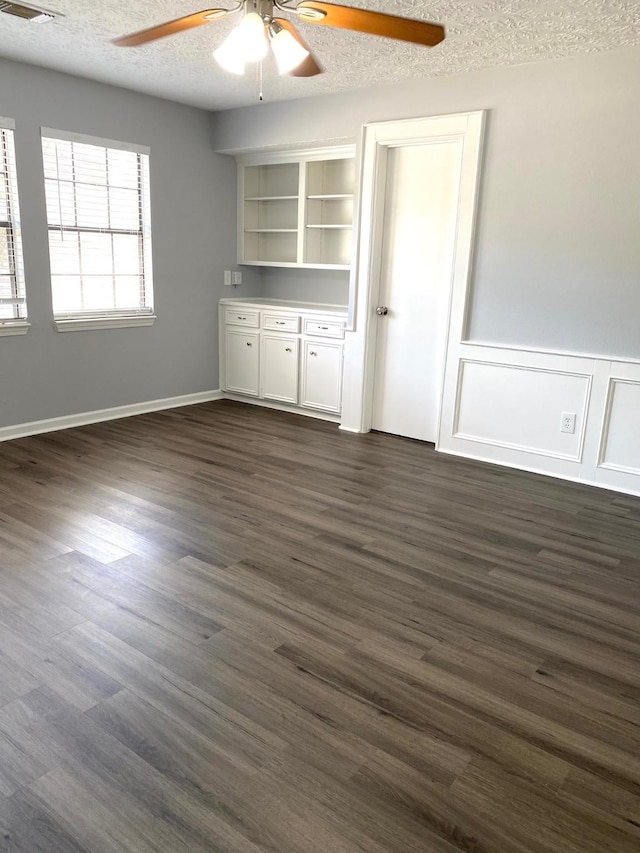 empty room with dark hardwood / wood-style flooring, ceiling fan, and a textured ceiling