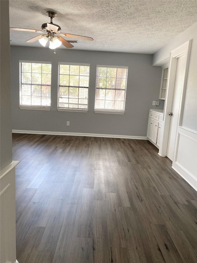 interior space with ceiling fan, plenty of natural light, dark hardwood / wood-style floors, and a textured ceiling