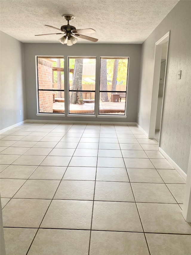 tiled empty room featuring ceiling fan and a textured ceiling