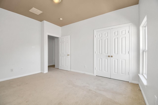 unfurnished bedroom featuring light colored carpet and a closet