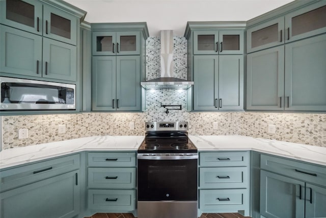 kitchen with tasteful backsplash, light stone counters, stainless steel appliances, and wall chimney exhaust hood