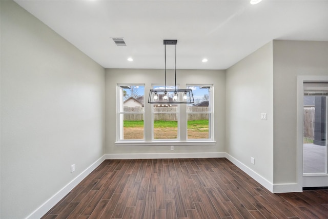 unfurnished dining area featuring dark wood-type flooring and an inviting chandelier