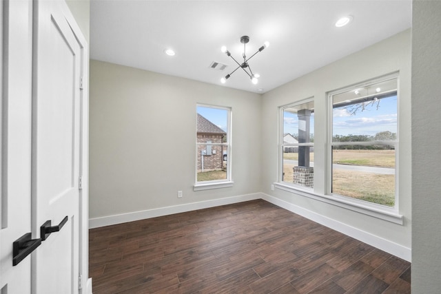 spare room with a chandelier and dark hardwood / wood-style flooring