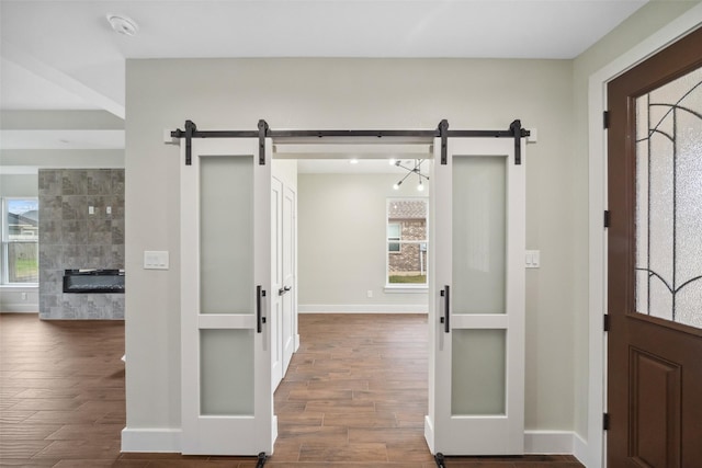 foyer with dark wood-type flooring, a fireplace, and a barn door