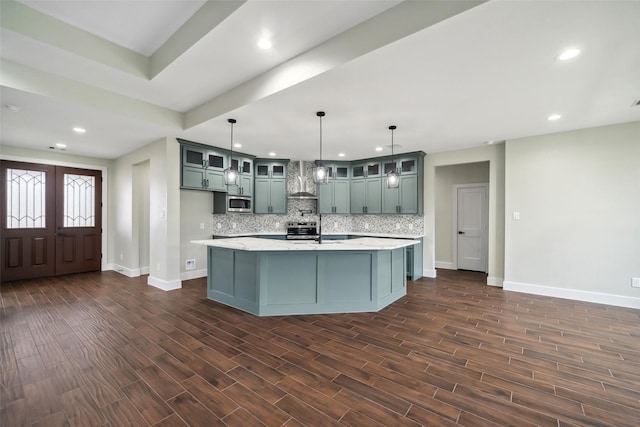 kitchen featuring tasteful backsplash, dark hardwood / wood-style floors, hanging light fixtures, and a center island with sink