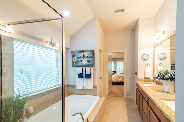 bathroom featuring tile patterned flooring, vanity, lofted ceiling, and tiled bath