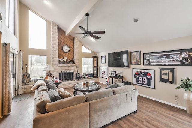 living room with wood-type flooring, high vaulted ceiling, a brick fireplace, beamed ceiling, and ceiling fan