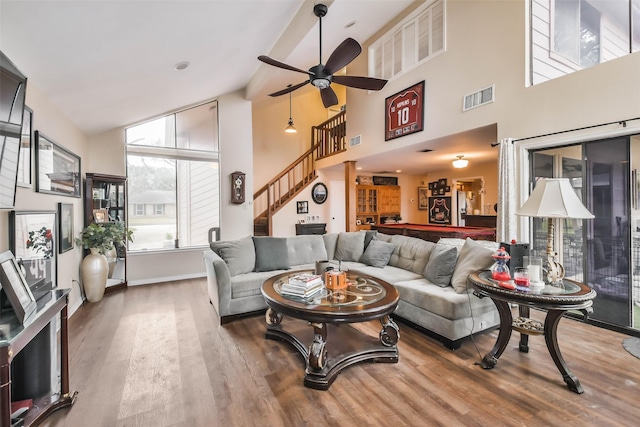 living room with wood-type flooring, high vaulted ceiling, and ceiling fan