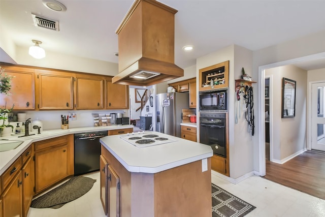 kitchen featuring sink, black appliances, a center island, and island exhaust hood