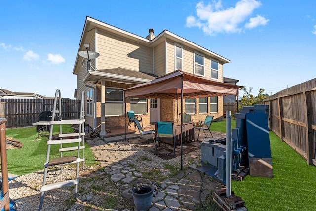 back of property featuring a gazebo and a lawn