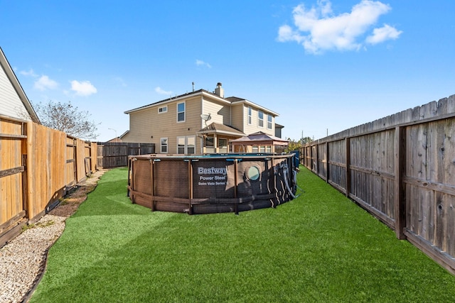 rear view of house with a fenced in pool, a gazebo, and a yard