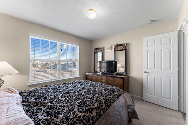 bedroom with light colored carpet and a textured ceiling