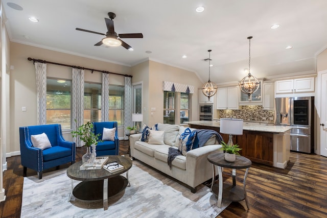 living room featuring ornamental molding, lofted ceiling, dark wood-type flooring, and ceiling fan with notable chandelier