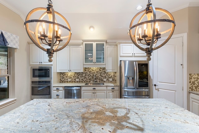 kitchen with stainless steel appliances, sink, light stone counters, and an inviting chandelier