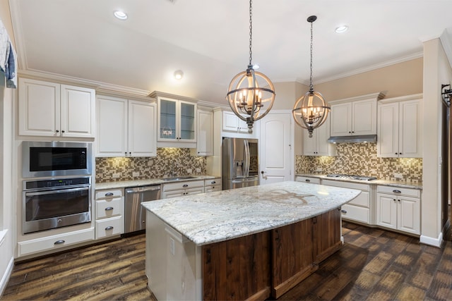 kitchen with stainless steel appliances, a kitchen island, hanging light fixtures, and light stone counters