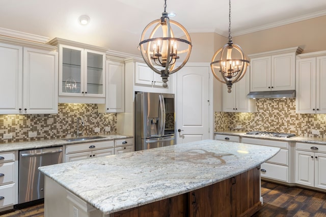 kitchen with sink, crown molding, hanging light fixtures, stainless steel appliances, and a kitchen island