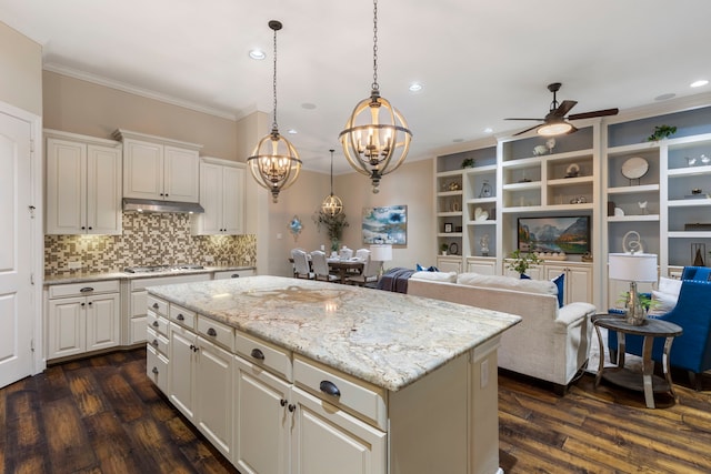 kitchen featuring crown molding, white cabinets, a kitchen island, decorative light fixtures, and stainless steel gas stovetop